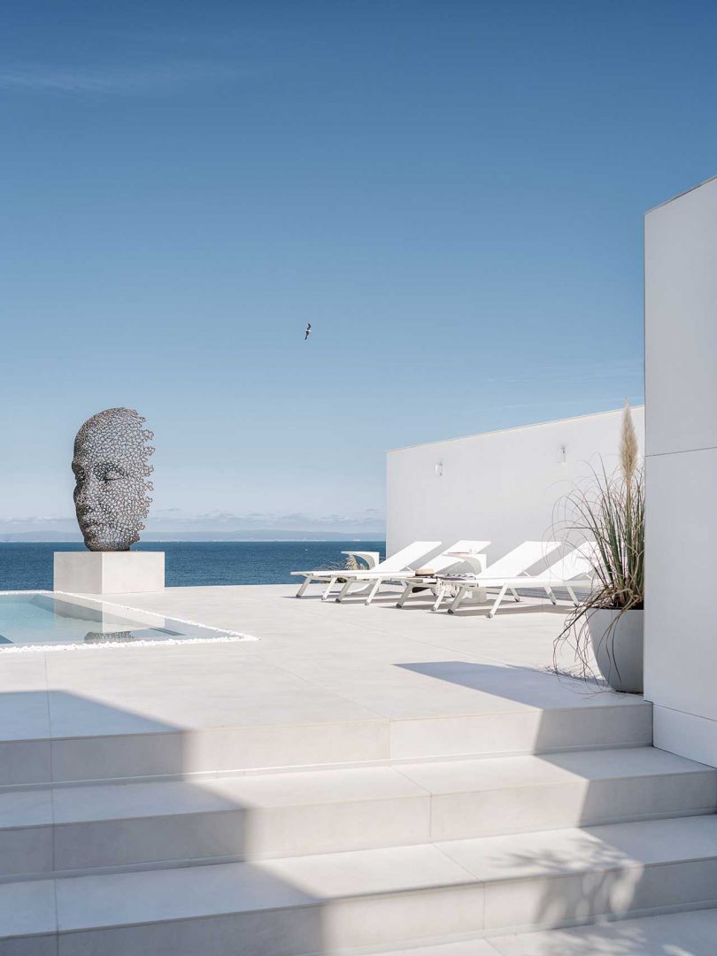 exterior minimalista de una casa blanca moderna con una zona de estar junto a la piscina