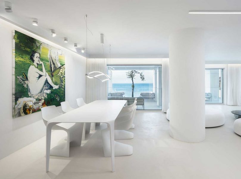 interior minimalista de una casa blanca moderna con un comedor con vista al océano