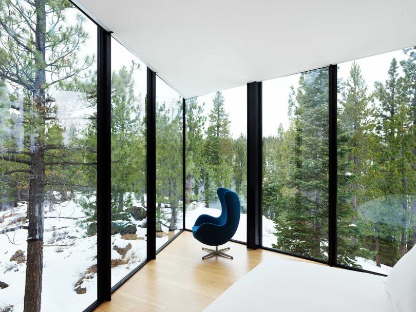 una esquina de un interior moderno con dos paredes de ventanas del piso al techo con una Egg Chair