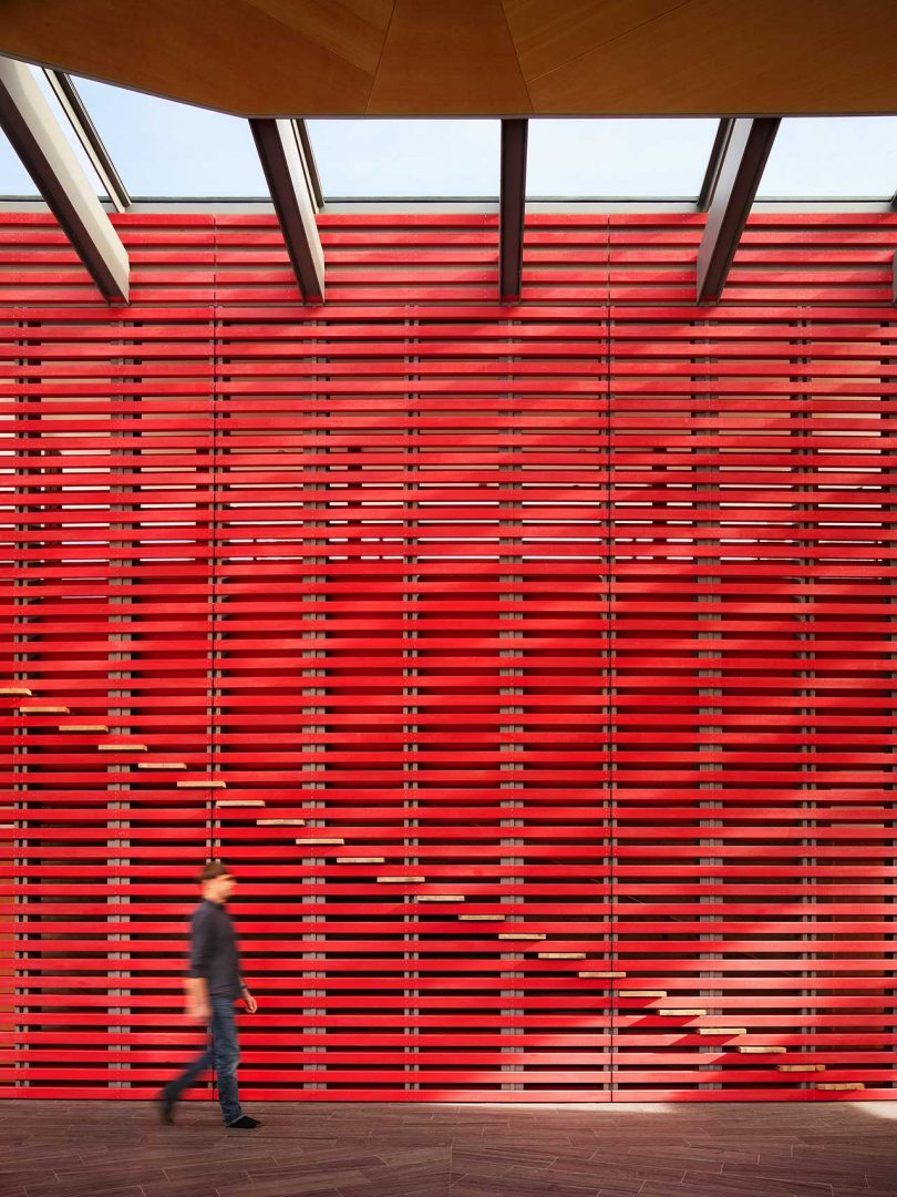 pared de listones rojos abierta de doble altura con escaleras más allá