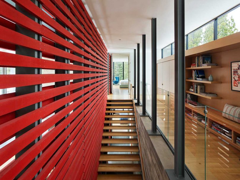 vista de la parte superior de una escalera abierta con una pared de rejilla roja abierta en un lado y un pasillo en el otro