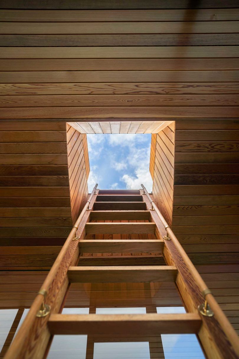 miró hacia arriba por la escalera hasta el techo de una moderna sauna flotante de madera en el agua