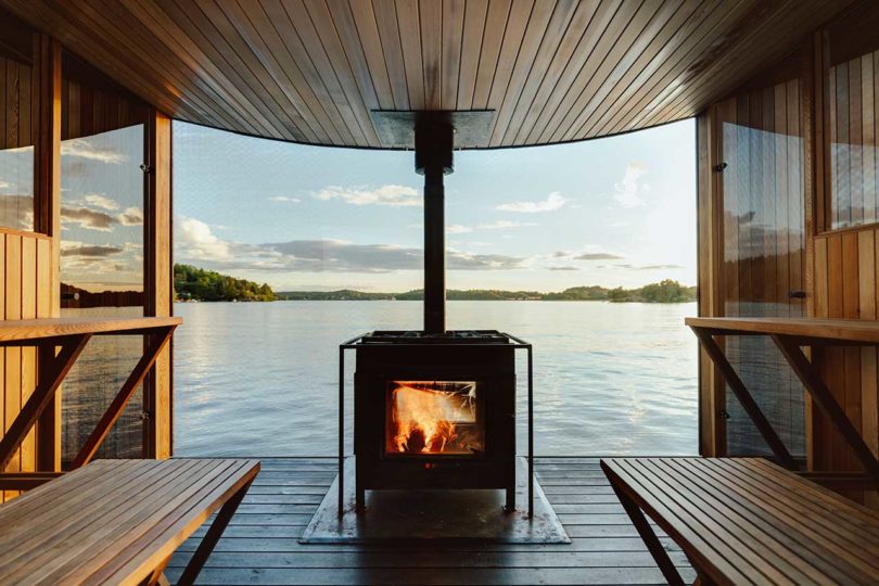 interior de una moderna sauna flotante de madera en el agua con fuego en llamas