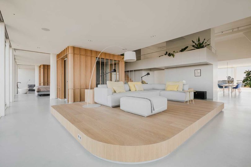 vista interior de la esquina de un moderno apartamento tipo loft con una plataforma de sofá de madera elevada
