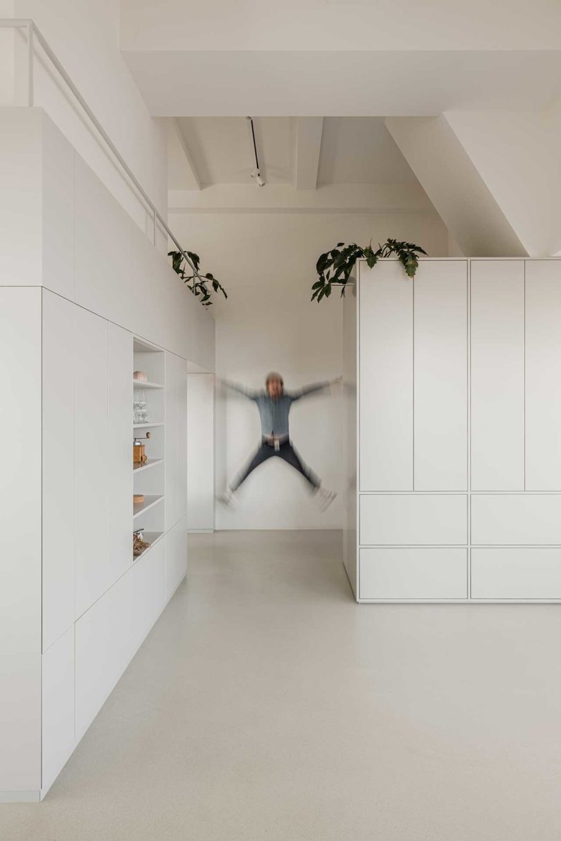 hombre saltando en el pasillo blanco de un apartamento moderno