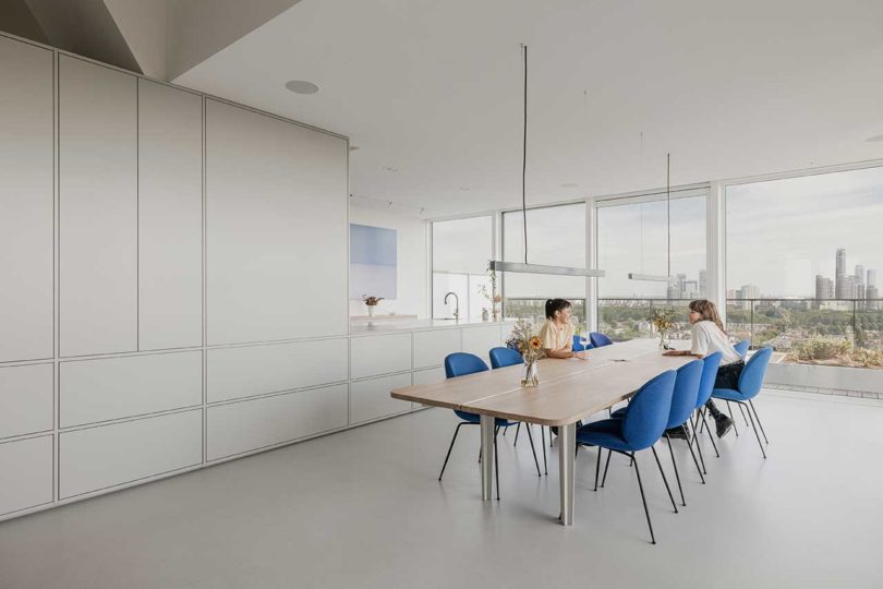 vista interior inclinada de cocina blanca moderna con mesa de comedor con sillas azules
